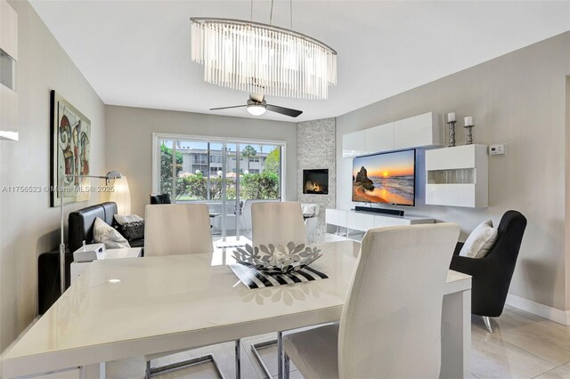 dining room featuring a fireplace, baseboards, and ceiling fan