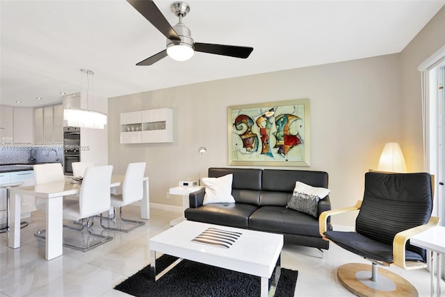 living area featuring a ceiling fan and baseboards