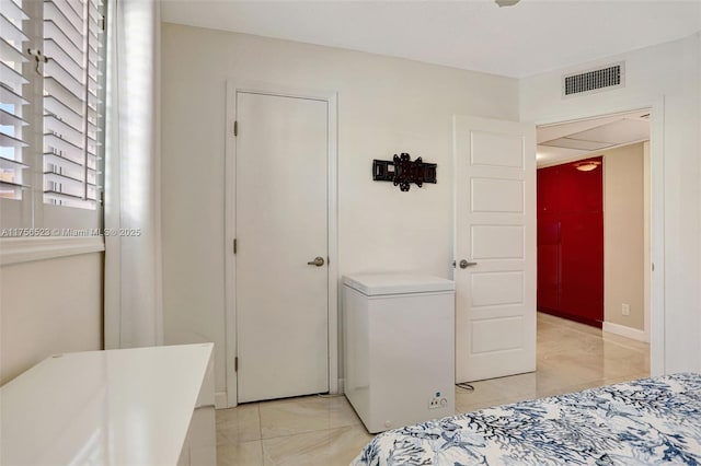 bedroom with visible vents and refrigerator