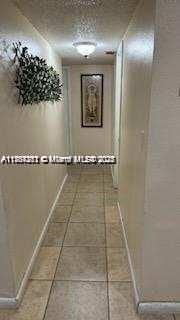 hallway with tile patterned flooring and baseboards