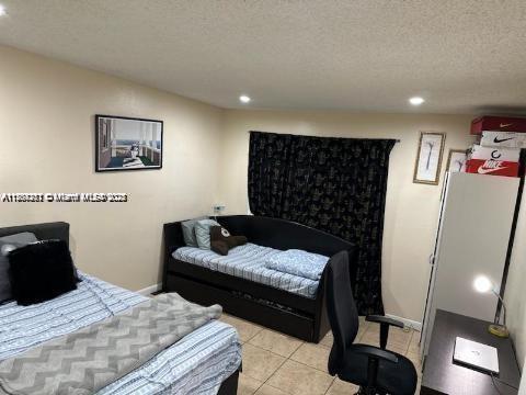 bedroom featuring light tile patterned floors, recessed lighting, a textured ceiling, and baseboards