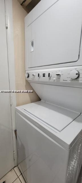 laundry room featuring light tile patterned floors, laundry area, and stacked washing maching and dryer