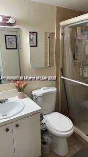 full bath featuring tile patterned flooring, toilet, lofted ceiling, a stall shower, and vanity