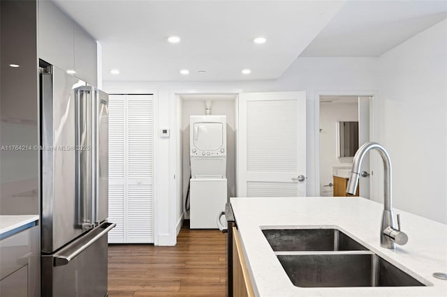 kitchen featuring recessed lighting, high end fridge, a sink, dark wood-type flooring, and stacked washer and dryer