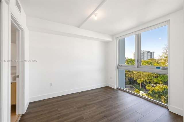 unfurnished room featuring dark wood-type flooring, visible vents, and baseboards