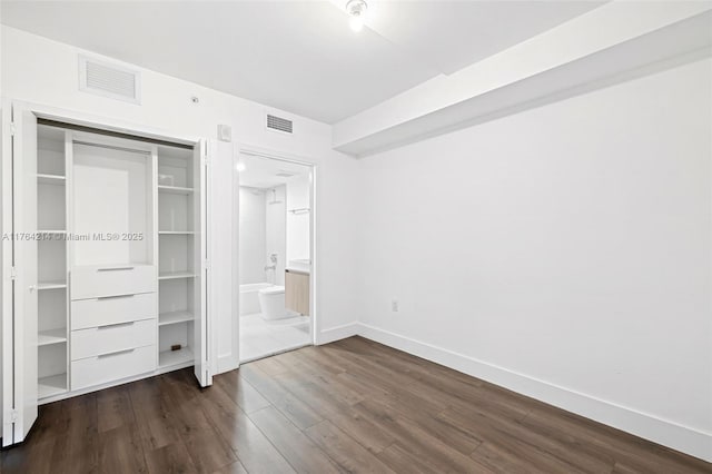 unfurnished bedroom featuring dark wood-style floors, visible vents, a closet, and baseboards