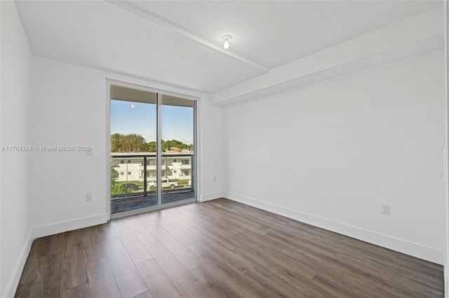 empty room with a wall of windows, baseboards, and dark wood finished floors