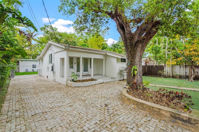 view of front of property with a porch, stucco siding, fence, and a front lawn