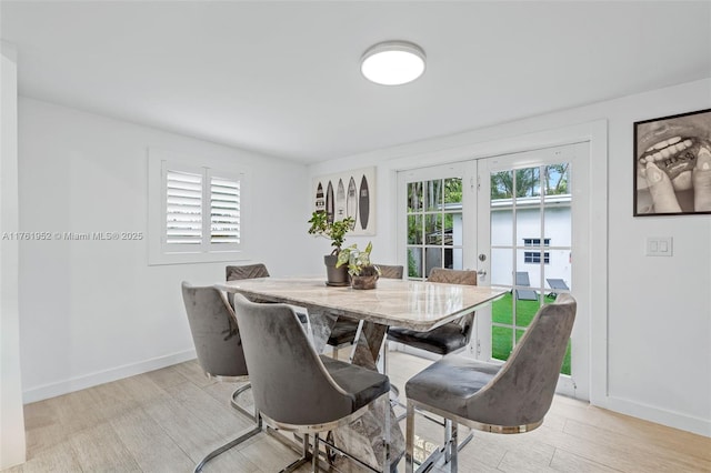 dining space with baseboards, light wood-style flooring, and french doors