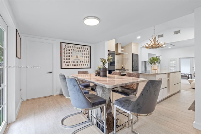 dining room featuring visible vents, vaulted ceiling, a chandelier, and light wood finished floors