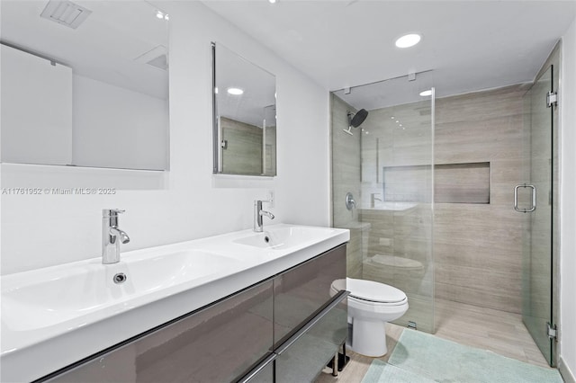 bathroom with recessed lighting, toilet, a sink, a stall shower, and double vanity