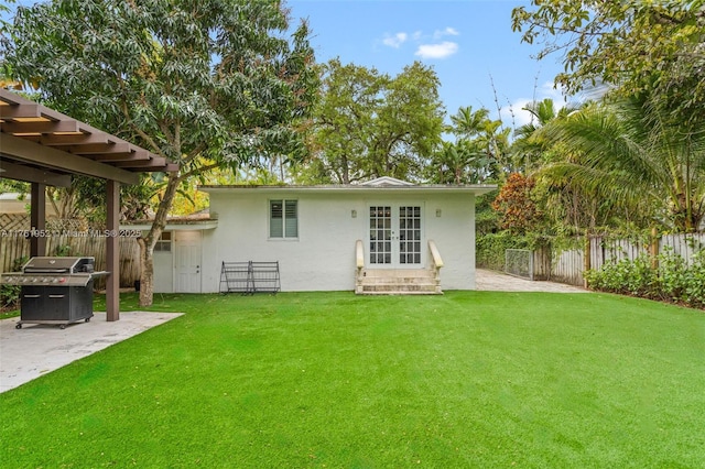 back of house featuring french doors, stucco siding, fence, a patio, and a lawn
