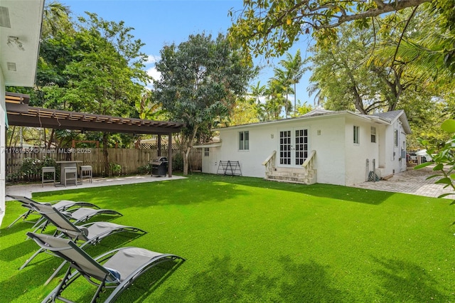rear view of house featuring a patio area, french doors, stucco siding, fence, and a yard