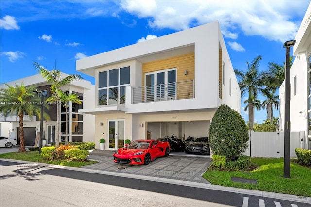 exterior space with stucco siding, driveway, fence, a garage, and a balcony