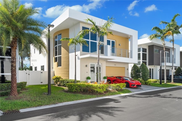 view of front facade featuring stucco siding, fence, an attached garage, and a gate