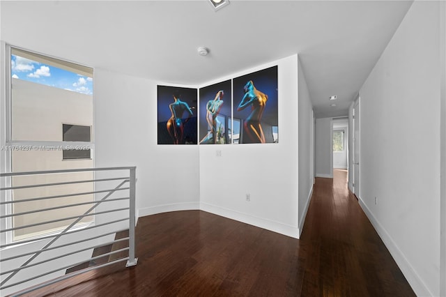 corridor with an upstairs landing, baseboards, and wood finished floors