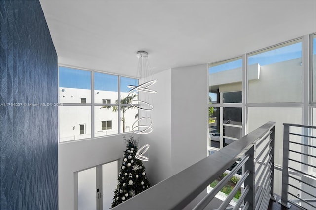 corridor with a notable chandelier and an upstairs landing