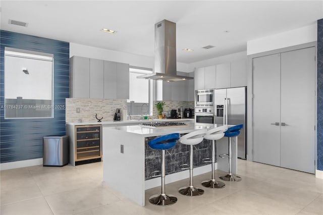 kitchen featuring visible vents, wine cooler, appliances with stainless steel finishes, modern cabinets, and island range hood