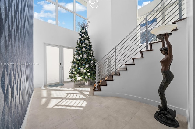 entrance foyer featuring stairs, baseboards, and a towering ceiling