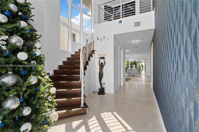 foyer with stairs, a high ceiling, baseboards, and visible vents