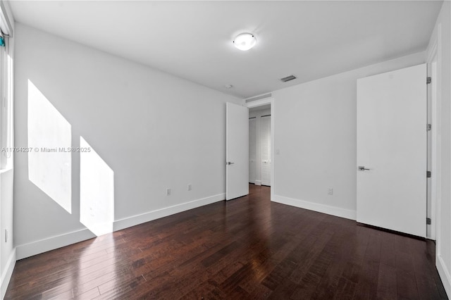 unfurnished bedroom with dark wood finished floors, visible vents, and baseboards