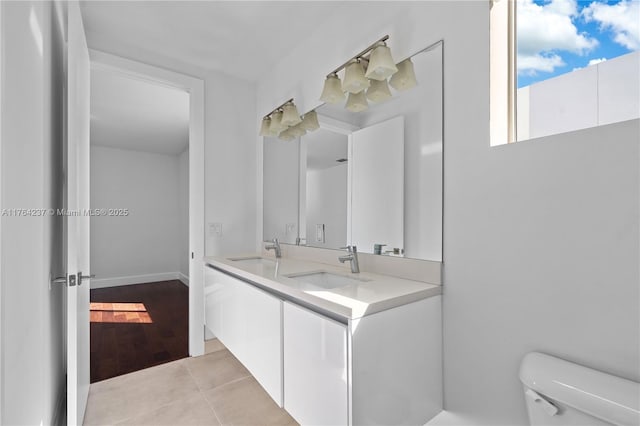 bathroom featuring a sink, toilet, double vanity, and tile patterned flooring