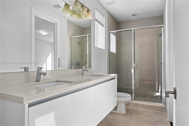 full bathroom featuring a sink, toilet, a stall shower, and tile patterned flooring