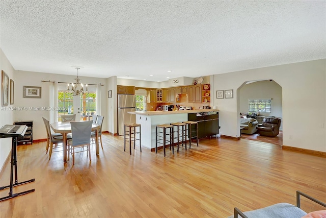 dining room with baseboards, arched walkways, an inviting chandelier, and light wood finished floors