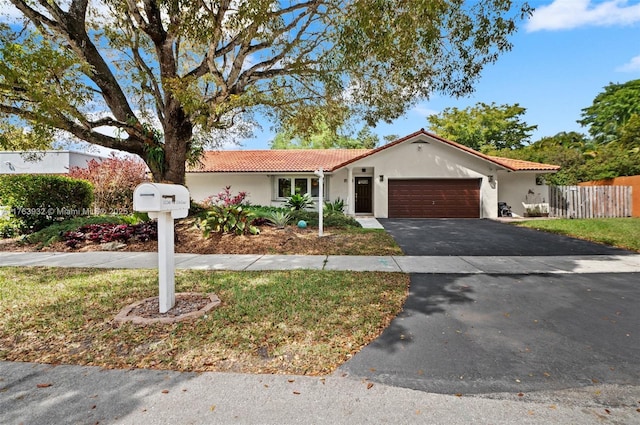 view of front of house with stucco siding, driveway, fence, an attached garage, and a tiled roof