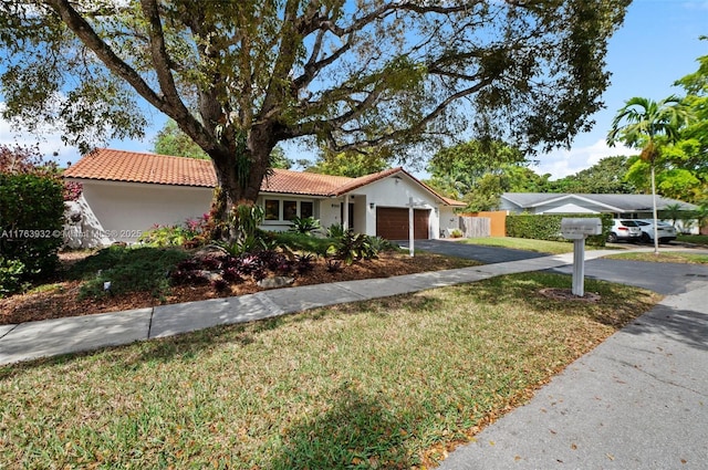 view of front facade with stucco siding, a front lawn, aphalt driveway, a garage, and a tiled roof