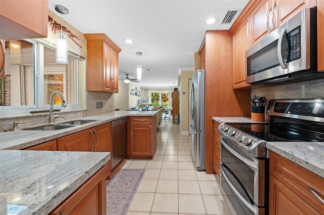 kitchen with backsplash, light tile patterned floors, light stone counters, stainless steel appliances, and a sink