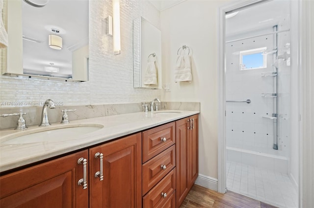 full bathroom featuring double vanity, backsplash, a tile shower, and a sink