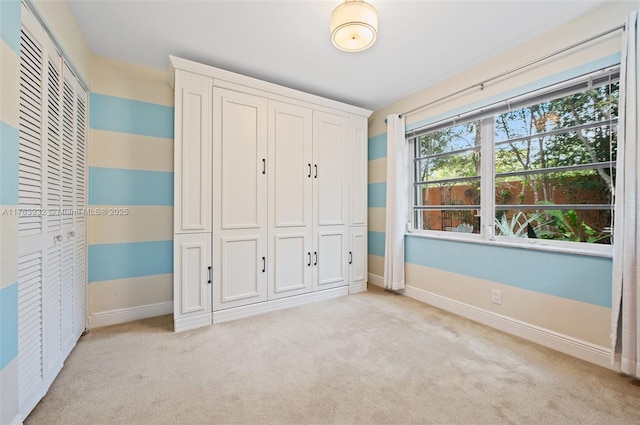 unfurnished bedroom with baseboards, light carpet, and a closet