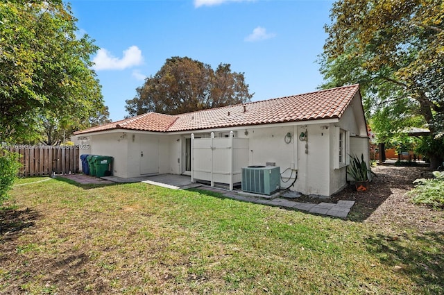 back of property featuring fence, central air condition unit, a tiled roof, stucco siding, and a yard