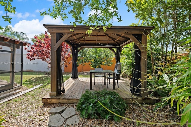 deck featuring a gazebo, outdoor dining area, and fence