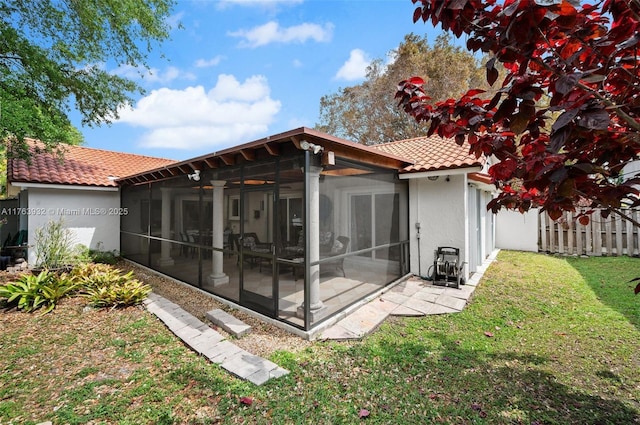 back of house with stucco siding, a sunroom, a yard, and a tile roof