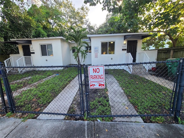 view of front facade featuring a gate, a fenced front yard, and stucco siding