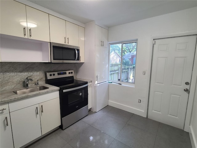 kitchen featuring tile patterned flooring, light countertops, white cabinets, stainless steel appliances, and a sink
