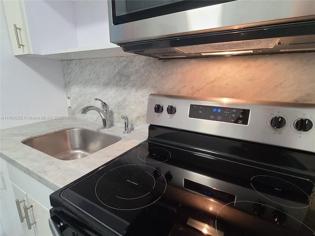 kitchen featuring a sink, tasteful backsplash, appliances with stainless steel finishes, and white cabinets
