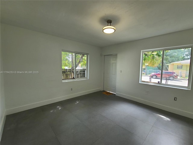 unfurnished room featuring baseboards and plenty of natural light