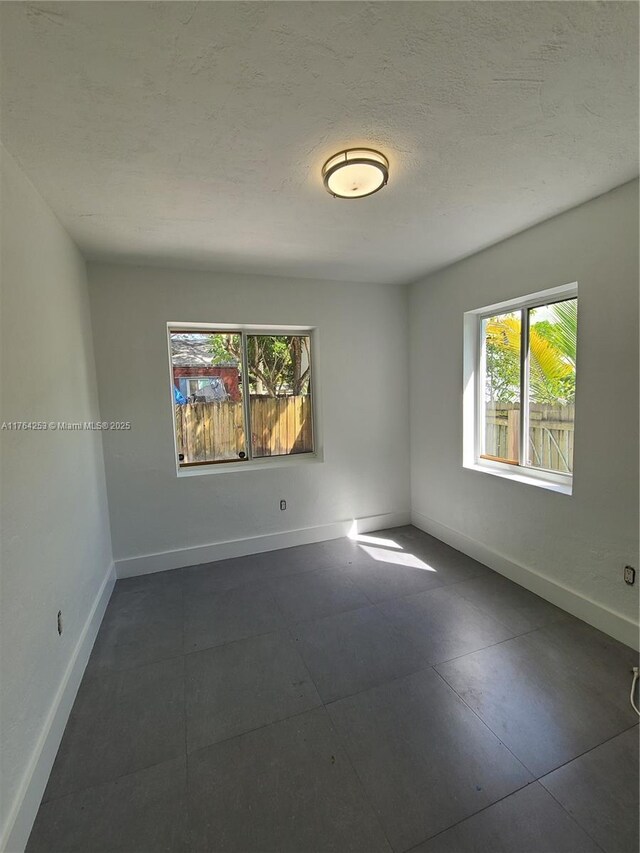 empty room with baseboards and a textured ceiling
