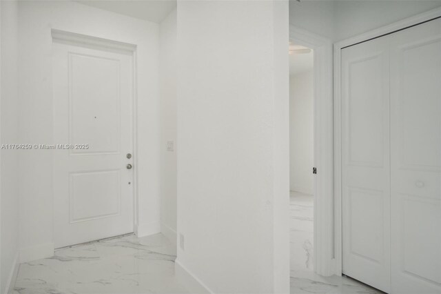 hallway featuring marble finish floor and baseboards