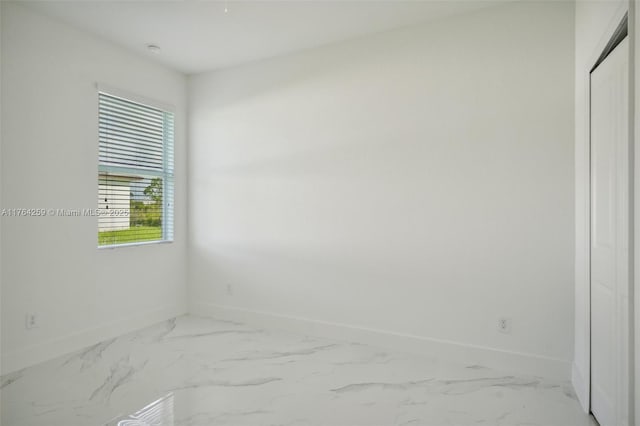 spare room featuring marble finish floor and baseboards