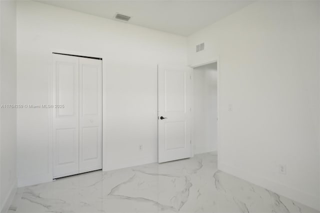 unfurnished bedroom featuring a closet, baseboards, visible vents, and marble finish floor