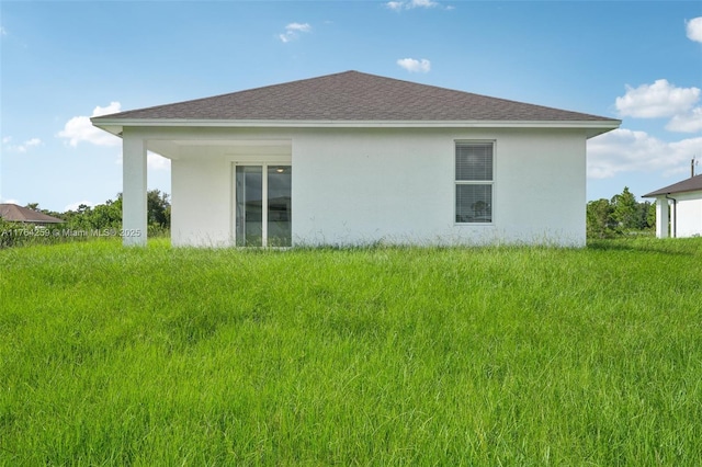 rear view of house with stucco siding and a shingled roof