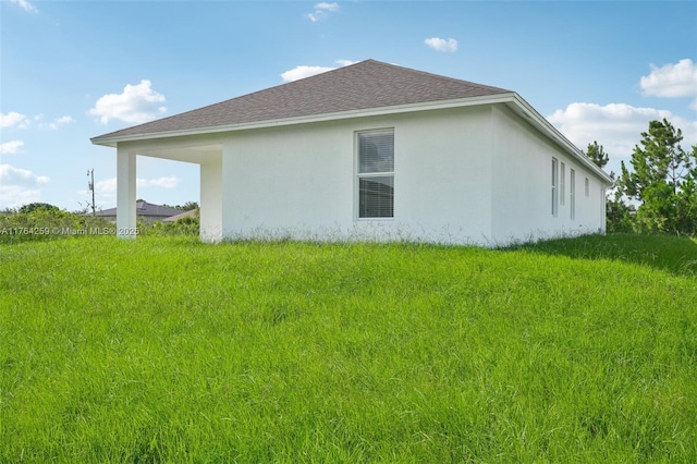 view of side of home with a carport, stucco siding, and roof with shingles