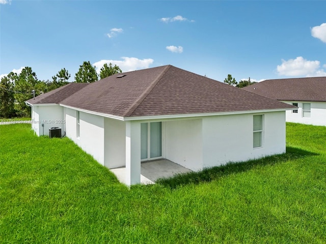 back of property featuring stucco siding, a lawn, a patio, central AC, and a shingled roof