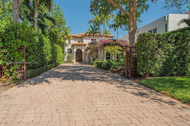 view of front facade featuring a tiled roof, decorative driveway, and stucco siding