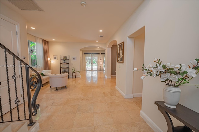 hall featuring visible vents, baseboards, stairway, recessed lighting, and arched walkways