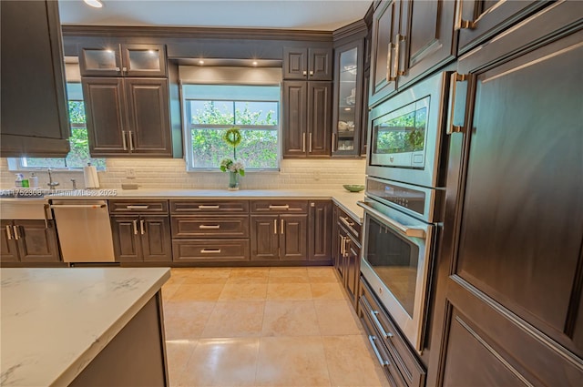 kitchen with decorative backsplash, dark brown cabinets, and appliances with stainless steel finishes